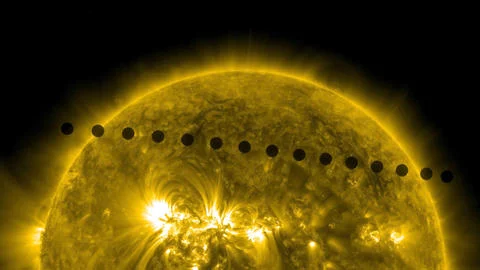 The image shows an image of the top half of the sun, with yellow aura and storms, and black sunspots. There are about 10 small, perfectly round, black dots spaced evenly in a line across the sun at a slight angle from horizontal. This is the planet Venus transiting (crossing) the sun.